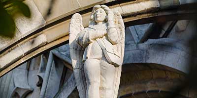 Statue of an angel holding a mobile phone in its hands